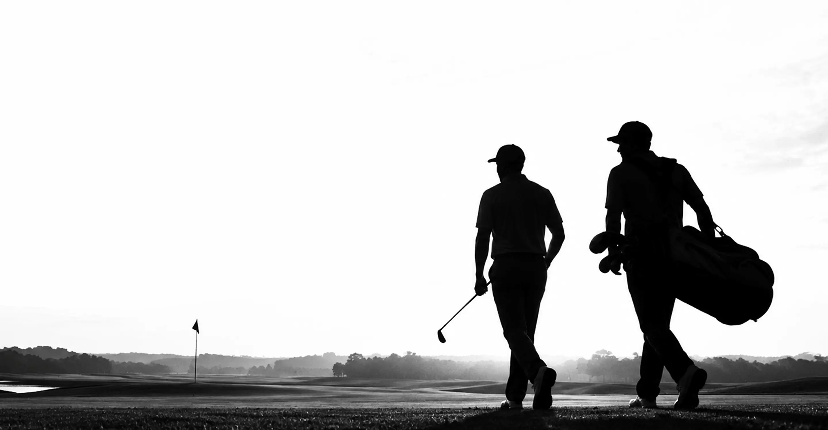 A golfer and caddie walking the fairway at first light.